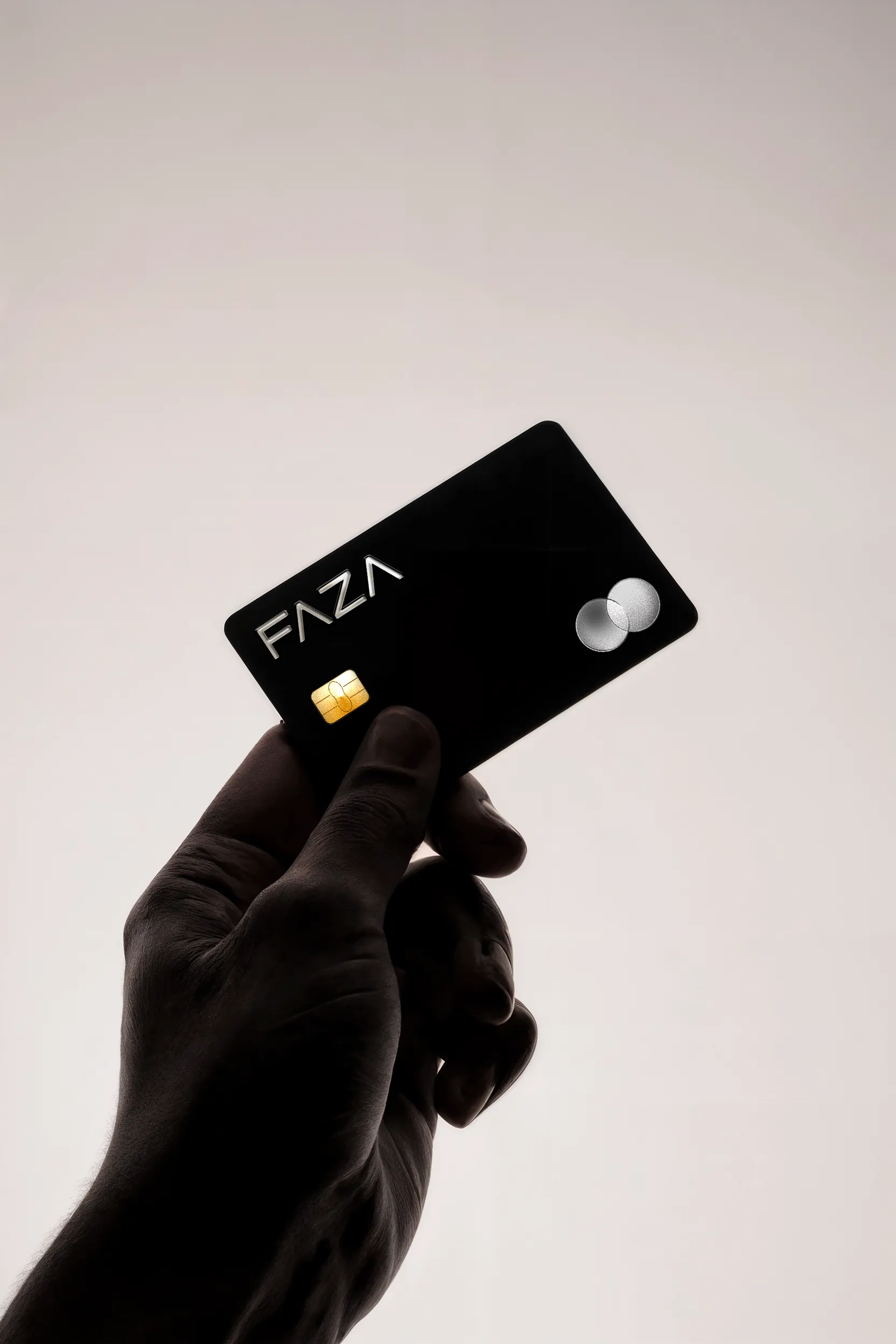 Hand holding a black FAZA virtual card