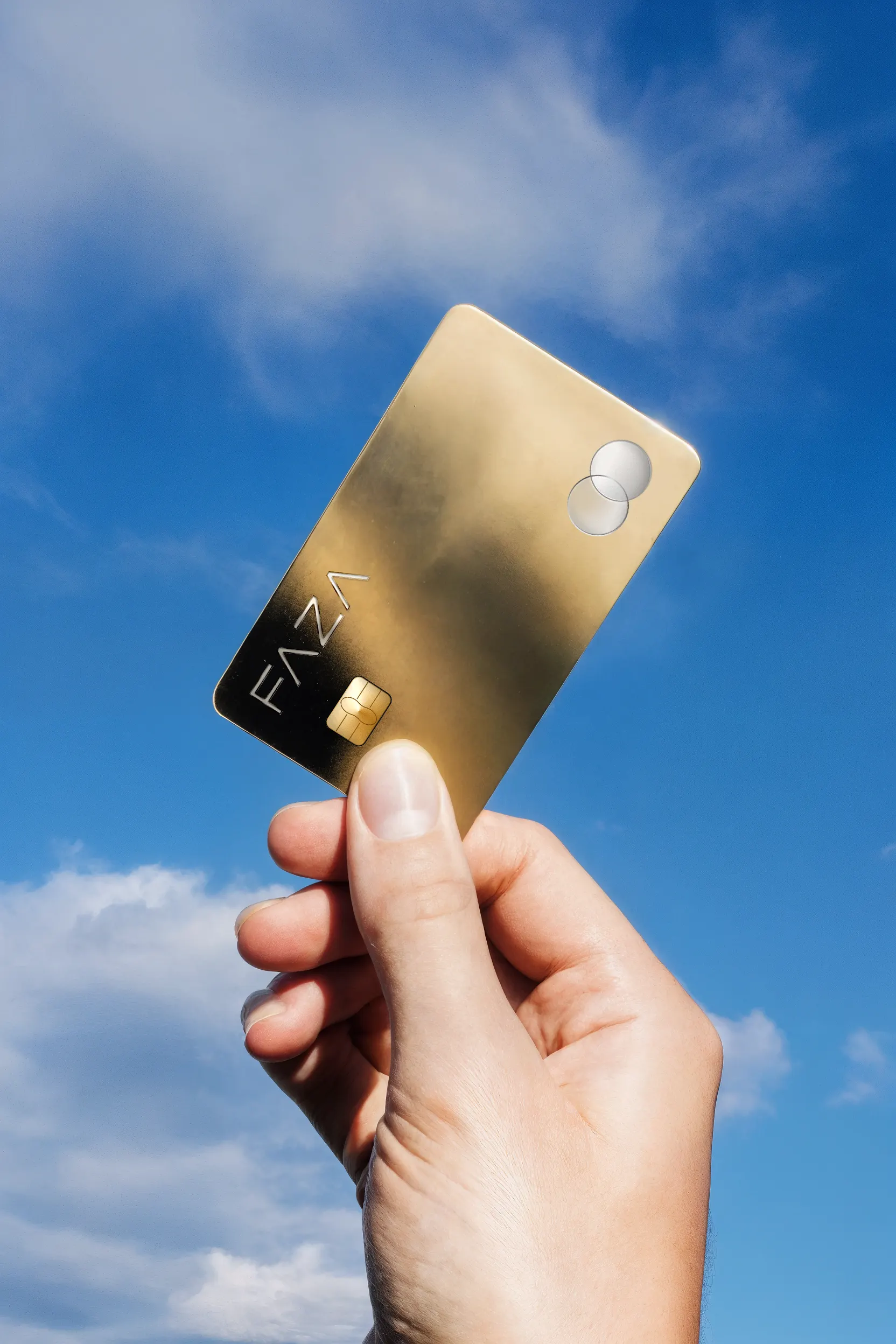 FAZA gold card held against a blue sky - global reach metaphor